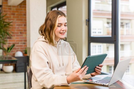 Photo for Pretty young woman with a laptop working at home. house interior design - Royalty Free Image