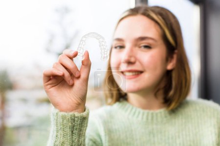 Photo for Pretty young woman holding a dental retainer. house interior design - Royalty Free Image
