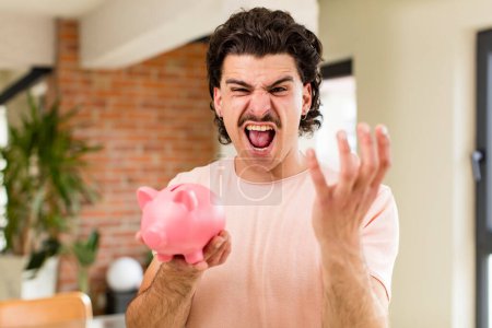 Photo for Young handsome man with a piggy bank. savings concept at home interior - Royalty Free Image