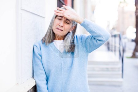 Photo for Senior retired pretty white hair woman looking stressed, tired and frustrated, drying sweat off forehead, feeling hopeless and exhausted - Royalty Free Image