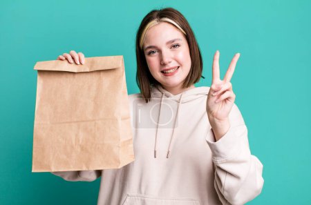 Photo for Young pretty woman with a take away paper bag - Royalty Free Image