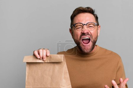 Photo for Middle age man looking angry, annoyed and frustrated. take away paper bag - Royalty Free Image