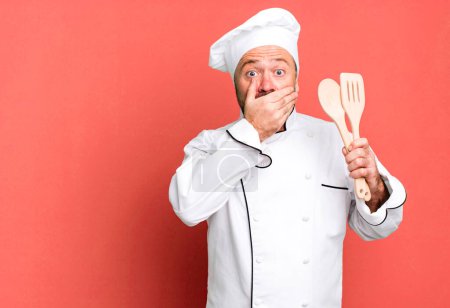 Photo for Middle age man covering mouth with hands with a shocked. chef and tools concept - Royalty Free Image