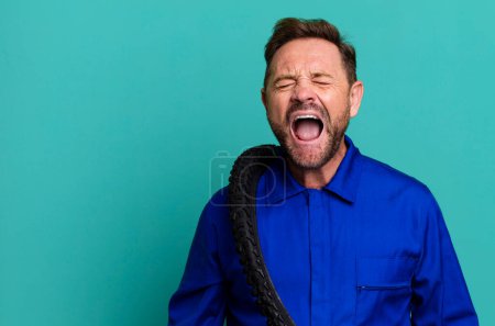 Photo for Middle age man shouting aggressively, looking very angry. bike repairman - Royalty Free Image
