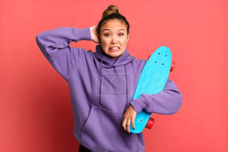 Photo for Hispanic pretty woman feeling stressed, anxious or scared, with hands on head. skate boarding concept - Royalty Free Image