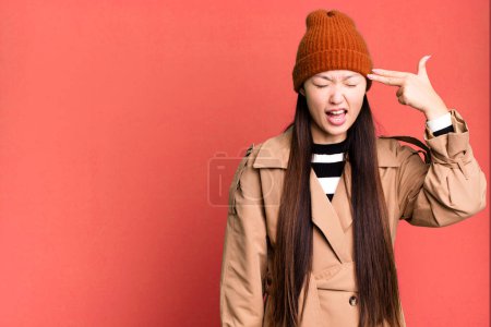 Foto de Bastante asiático mujer buscando infeliz y estresado, suicidio gesto haciendo arma signo - Imagen libre de derechos