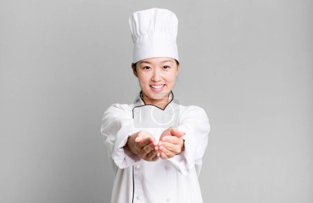 Foto de Bonita mujer asiática sonriendo felizmente con amable y ofreciendo y mostrando un concepto. concepto de chef restaurante - Imagen libre de derechos