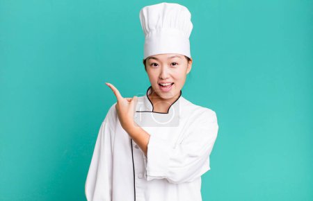 Photo for Pretty asian woman looking excited and surprised pointing to the side. restaurant chef concept - Royalty Free Image