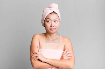 Foto de Bonita mujer asiática encogiéndose de hombros, sintiéndose confundida e incierta. concepto de belleza y ducha - Imagen libre de derechos