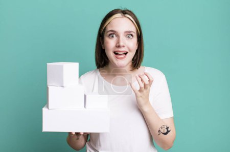 Foto de Joven bonita mujer buscando desesperado, frustrado y estresado. cajas blancas en blanco - Imagen libre de derechos