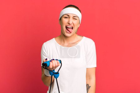 Photo for Young pretty woman with cheerful and rebellious attitude, joking and sticking tongue out. fitness concept - Royalty Free Image