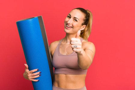 Photo for Young pretty woman feeling proud,smiling positively with thumbs up. fitness and yoga concept - Royalty Free Image