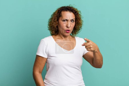 Téléchargez les photos : Femme hispanique d'âge moyen pointant vers la caméra avec une expression agressive en colère ressemblant à un patron furieux et fou - en image libre de droit