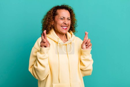 Photo for Middle age hispanic woman feeling nervous and hopeful, crossing fingers, praying and hoping for good luck - Royalty Free Image