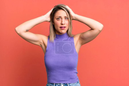 Photo for Blonde adult woman feeling stressed, worried, anxious or scared, with hands on head, panicking at mistake - Royalty Free Image