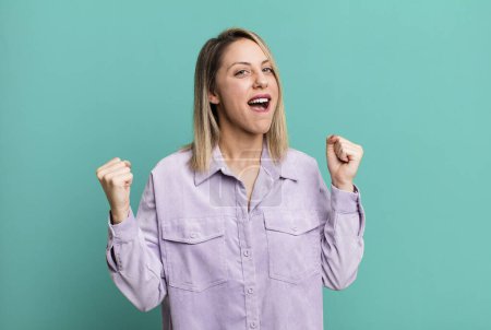 Photo for Blonde adult woman feeling happy, surprised and proud, shouting and celebrating success with a big smile - Royalty Free Image