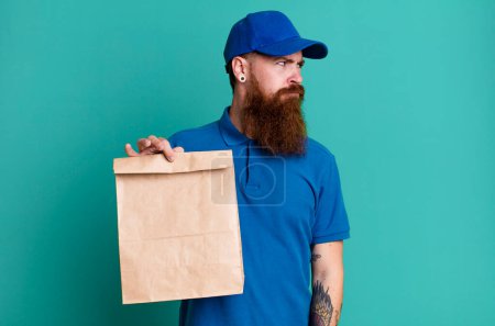 Téléchargez les photos : Jeune adulte cheveux roux barbu livraison fraîche homme avec un sac en papier - en image libre de droit