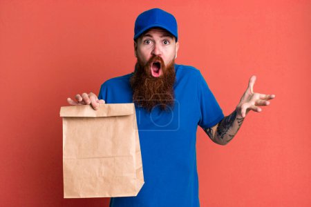 Téléchargez les photos : Jeune adulte cheveux roux barbu livraison fraîche homme avec un sac en papier - en image libre de droit
