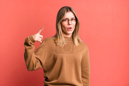 Photo for Blonde pretty woman pointing at camera with an angry aggressive expression looking like a furious, crazy boss - Royalty Free Image