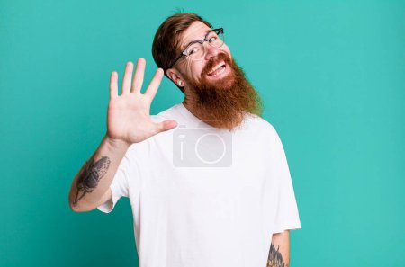 Téléchargez les photos : Longue barbe et cheveux roux homme souriant heureux, agitant la main, vous accueillant et vous saluant - en image libre de droit