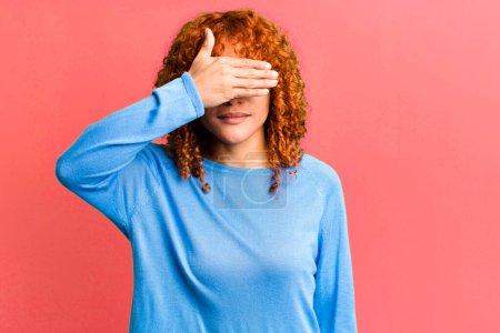 Photo for Redhair pretty woman covering eyes with one hand feeling scared or anxious, wondering or blindly waiting for a surprise - Royalty Free Image