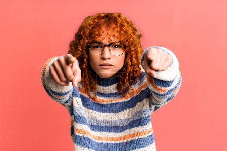 Photo for Redhair pretty woman pointing forward at camera with both fingers and angry expression, telling you to do your duty - Royalty Free Image
