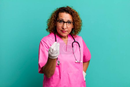 Photo for Pretty middle age woman making capice or money gesture, telling you to pay. nurse concept - Royalty Free Image