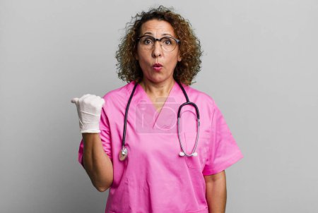 Photo for Pretty middle age woman looking astonished in disbelief. nurse concept - Royalty Free Image