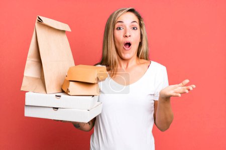 Photo for Pretty blonde woman feeling extremely shocked and surprised. delivery take away food packages concept - Royalty Free Image