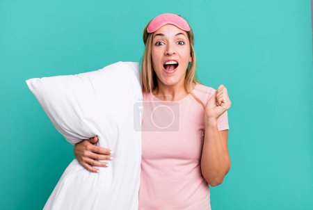 Photo for Pretty blonde woman feeling shocked,laughing and celebrating success. pajamas or nightwear concept - Royalty Free Image