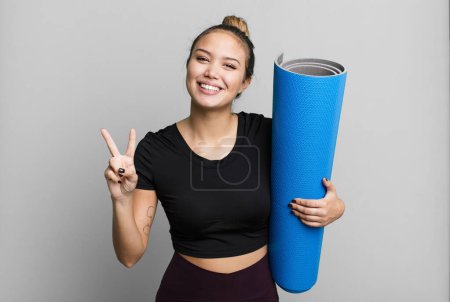 Photo for Hispanic pretty woman smiling and looking friendly, showing number two. fitness and yoga concept - Royalty Free Image