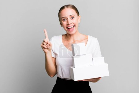 Téléchargez les photos : Caucasienne jolie femme se sentant comme un génie heureux et excité après avoir réalisé une idée avec boîtes blanches paquets - en image libre de droit