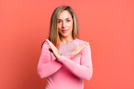 Photo for Blonde adult woman looking annoyed and sick of your attitude, saying enough! hands crossed up front, telling you to stop - Royalty Free Image