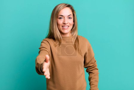 Photo for Blonde adult woman smiling, looking happy, confident and friendly, offering a handshake to close a deal, cooperating - Royalty Free Image