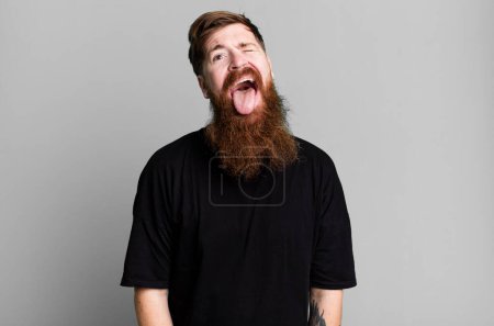 Photo for Long beard and red hair man with cheerful and rebellious attitude, joking and sticking tongue out - Royalty Free Image
