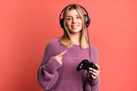 Photo for Young pretty woman looking excited and surprised pointing to the side. gamer with headset and controller - Royalty Free Image