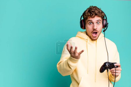Photo for Young adult caucasian man feeling extremely shocked and surprised with headset and a controller. gamer concept - Royalty Free Image