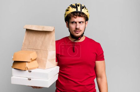 Photo for Young adult caucasian man feeling sad, upset or angry and looking to the side.  take away fast food deliveryman concept - Royalty Free Image
