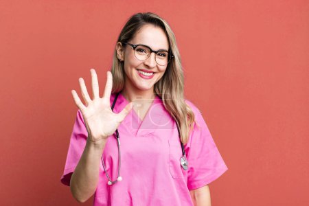 Photo for Smiling and looking friendly, showing number five. nurse concept - Royalty Free Image