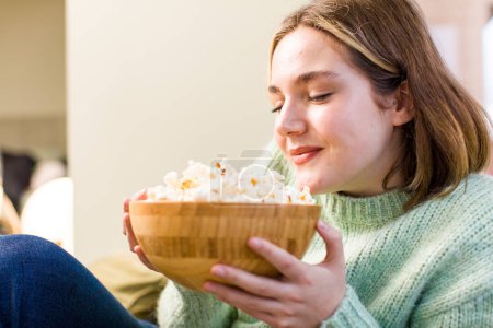 Téléchargez les photos : Jolie jeune femme avec un bol de popcorns.. design d'intérieur de la maison - en image libre de droit