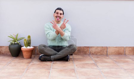 Photo for Young handsome man gardering and sitting on the floor outdoors - Royalty Free Image