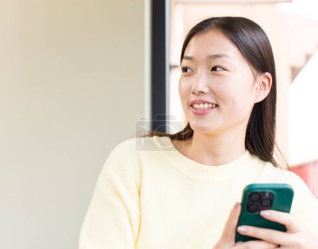 Téléchargez les photos : Asiatique jolie femme à l'aide d'un smartphone et shopping à la maison - en image libre de droit