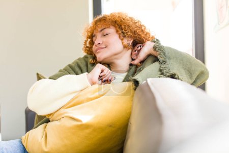 Téléchargez les photos : Jeune rousse cheveux latins jolie femme reposant sur un canapé à la maison - en image libre de droit