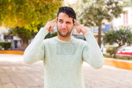 Photo for Young hispanic man feeling confused or doubting, concentrating on an idea, looking to copy space on side - Royalty Free Image