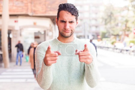 Photo for Young hispanic man pointing forward at camera with both fingers and angry expression, telling you to do your duty - Royalty Free Image