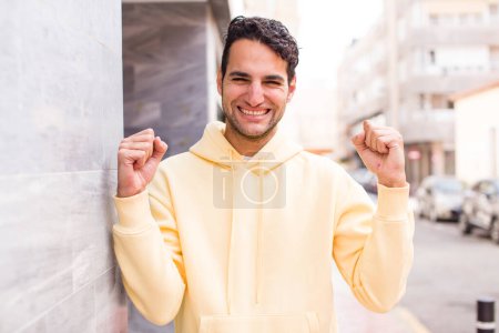 Photo for Young hispanic man shouting aggressively with an angry expression or with fists clenched celebrating success - Royalty Free Image