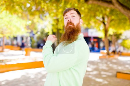 Photo for Red hair bearded man feeling happy, positive and successful, money concept and celebrating good results - Royalty Free Image