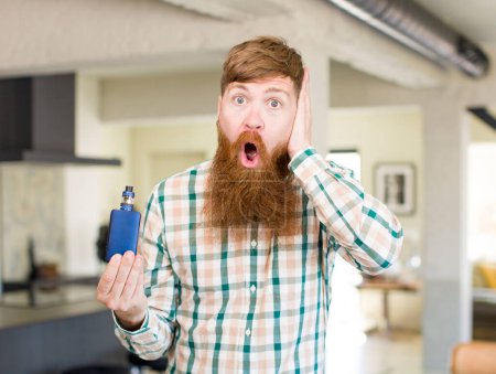 Photo for Red hair man feeling extremely shocked and surprised with a vaper - Royalty Free Image