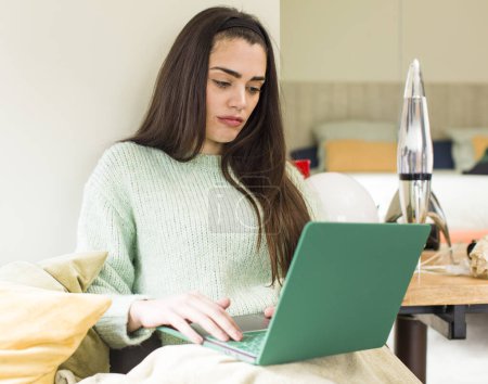 Téléchargez les photos : Jolie jeune femme travaillant à la maison avec un ordinateur portable. design intérieur de la maison - en image libre de droit