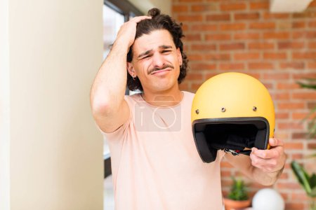 Foto de Joven hombre guapo sosteniendo un casco de moto en el interior de casa - Imagen libre de derechos